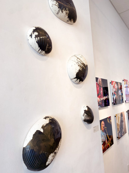 Decorative wall art pieces on a white wall with framed photographs below.