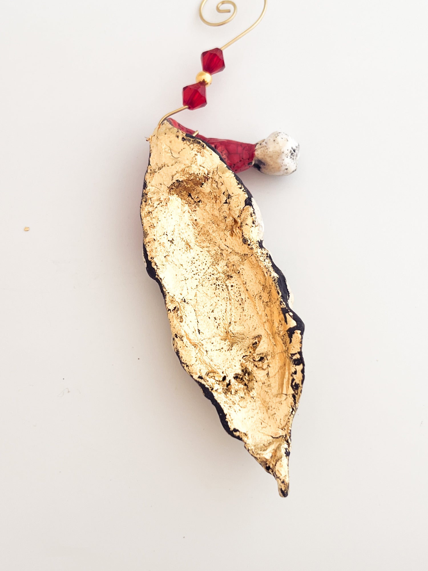Decorative gold leaf ornament with red beads on a white background