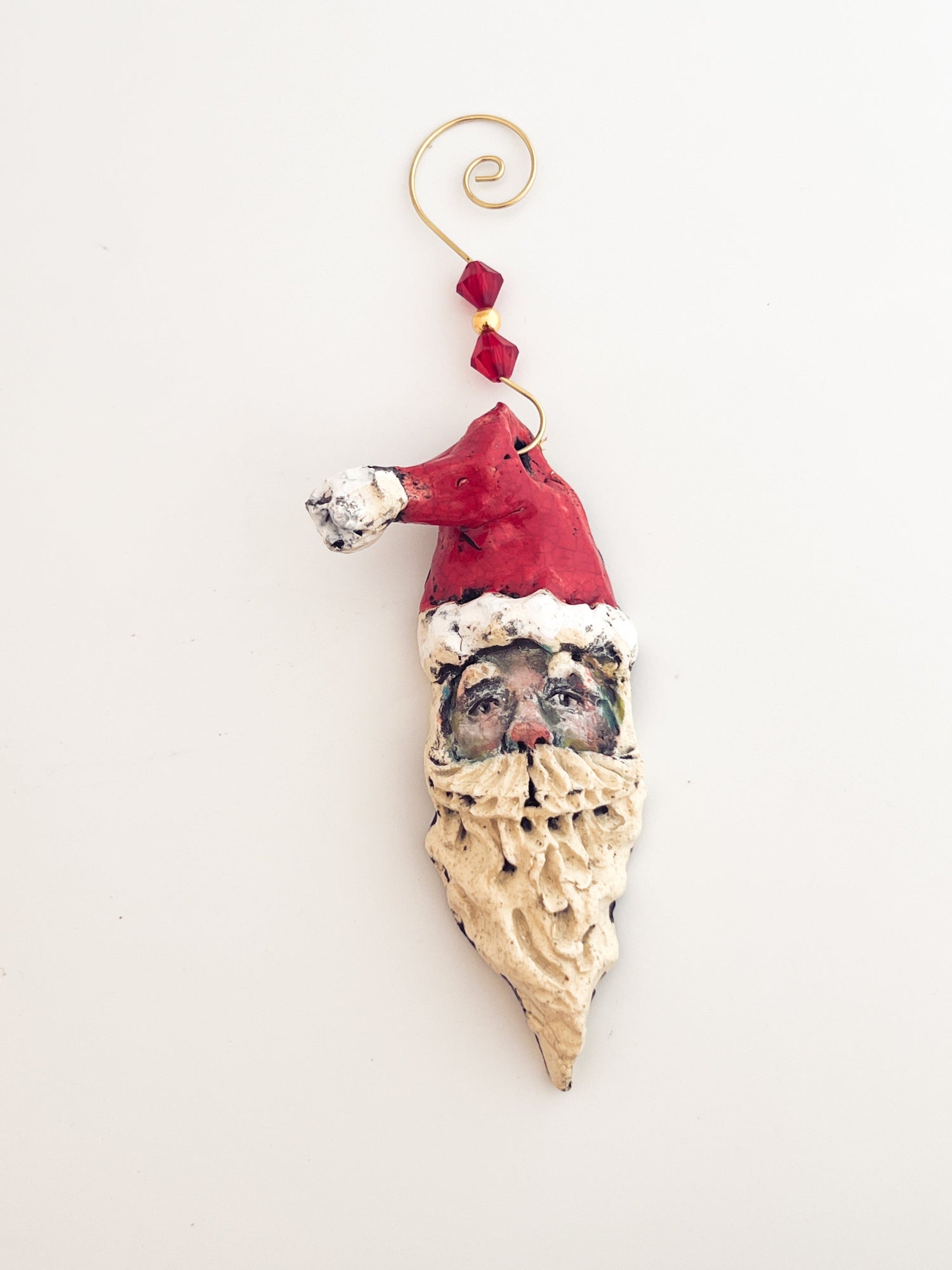 Decorative ornament shaped like a face wearing a Santa hat on a white background