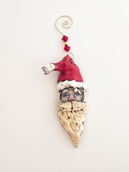 Decorative ornament shaped like a face wearing a Santa hat on a white background