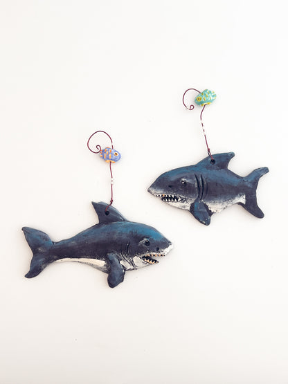 Two shark-shaped toys with string handles on a white background