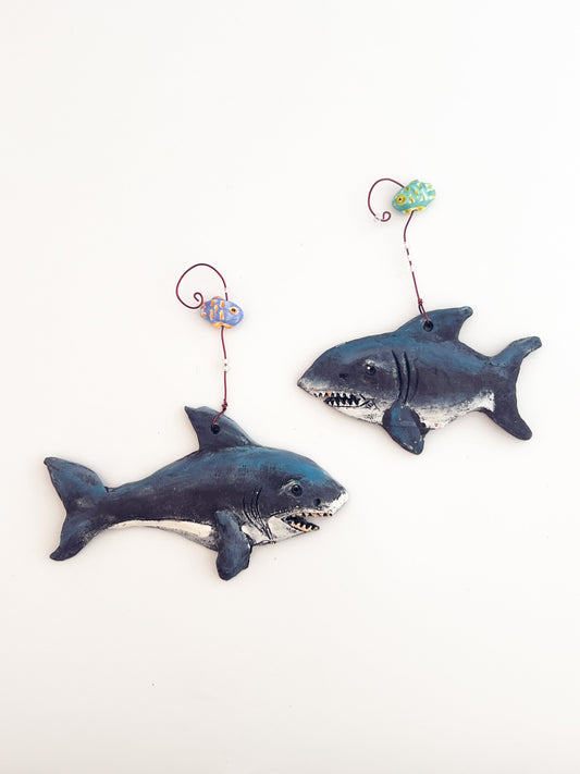 Two shark-shaped toys with string handles on a white background