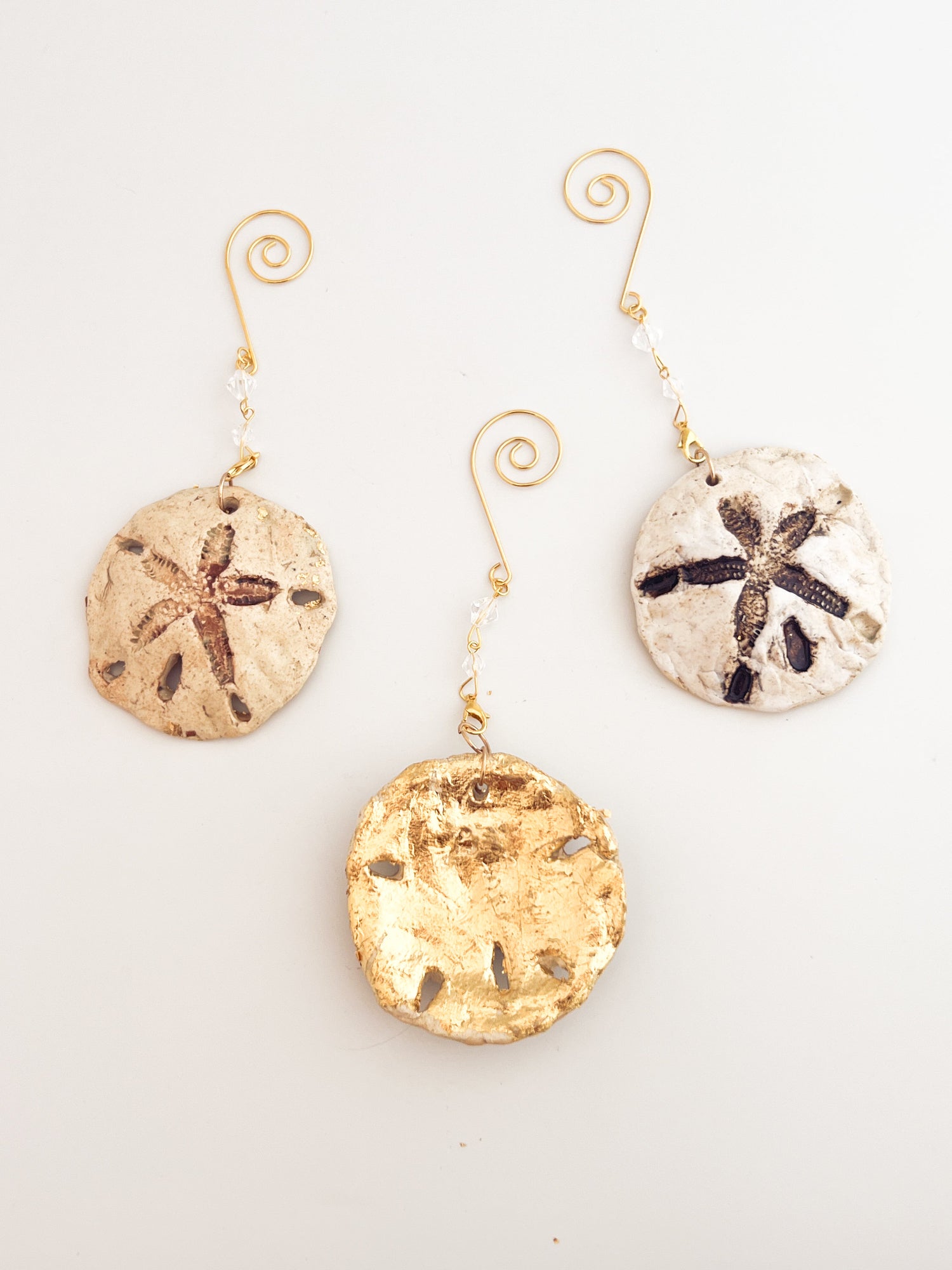 Set of three sand dollar ornaments on a light gray background