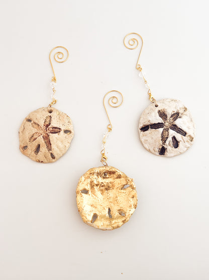 Set of three sand dollar ornaments on a light gray background