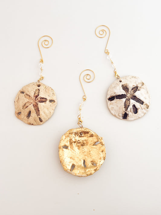 Set of three sand dollar ornaments on a light gray background