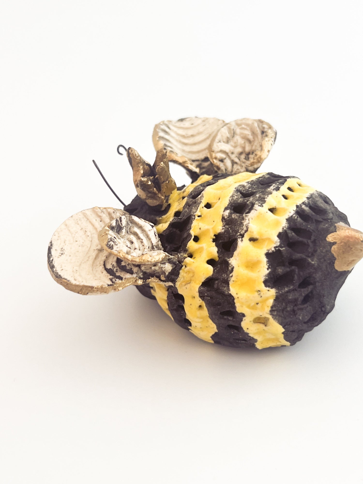 Decorative bee figure with black, yellow, and gold colors on a white background