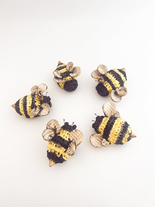 Five small ceramic bee sculptures on a white background